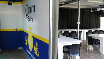 A room with a Corona Extra branded wall, a white table, and black chairs.