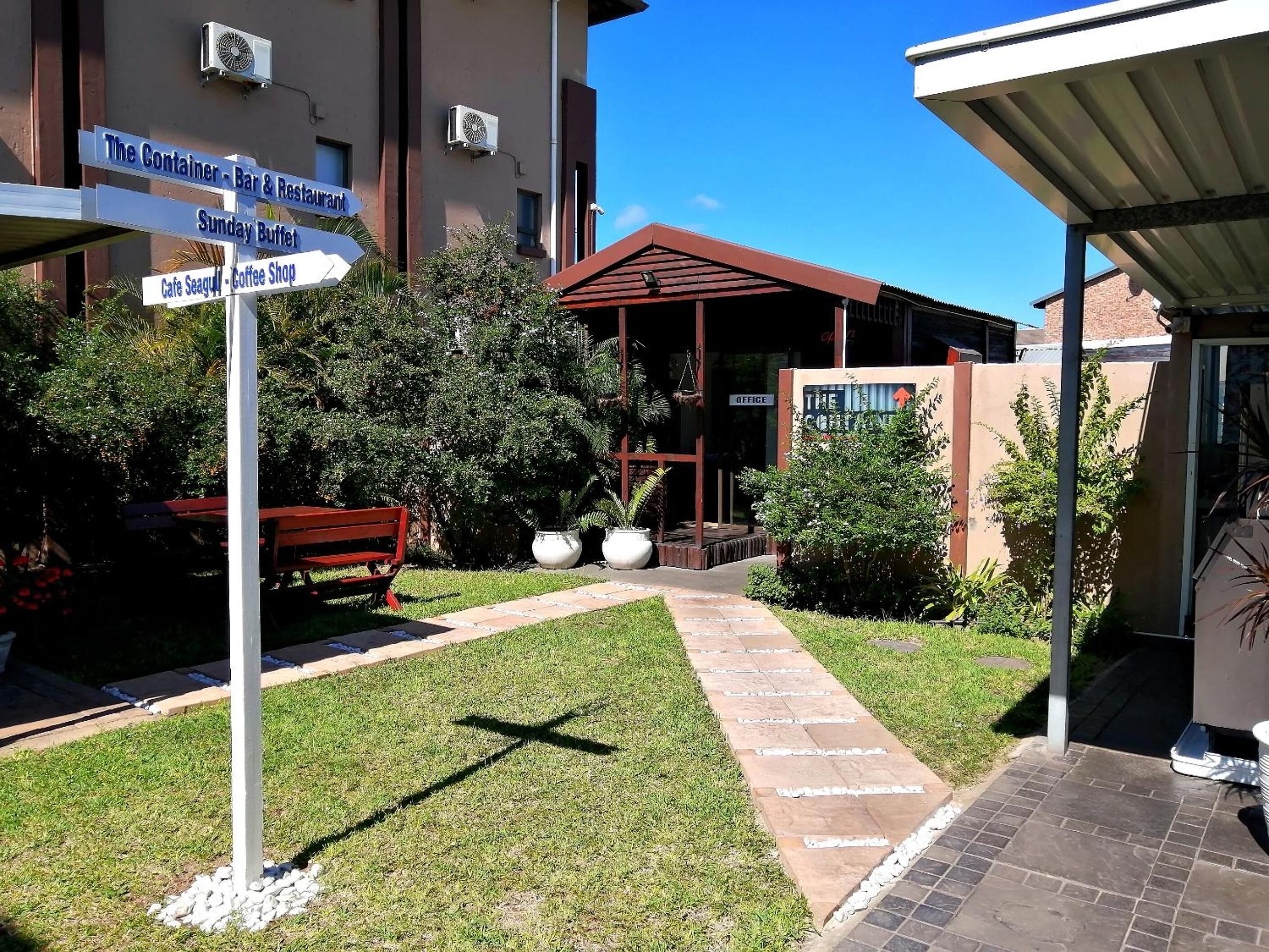 A courtyard with a signpost indicating nearby amenities like a bar, restaurant, and coffee shop.