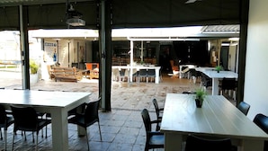 Un café en plein air avec des tables et des chaises, un coin bar et une vue sur la rue.