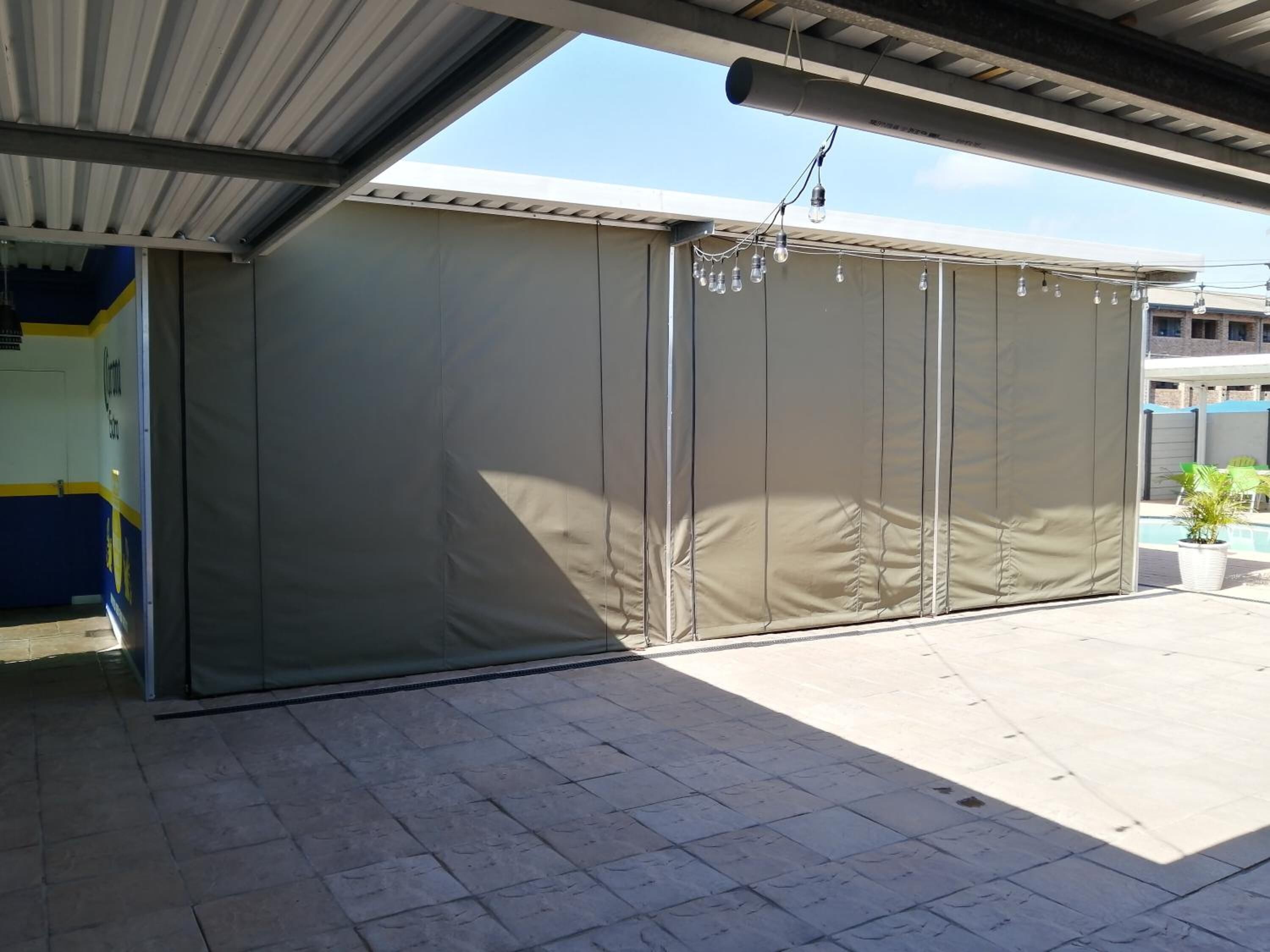 Un espacio al aire libre techado con un toldo grande, beige y retráctil.
