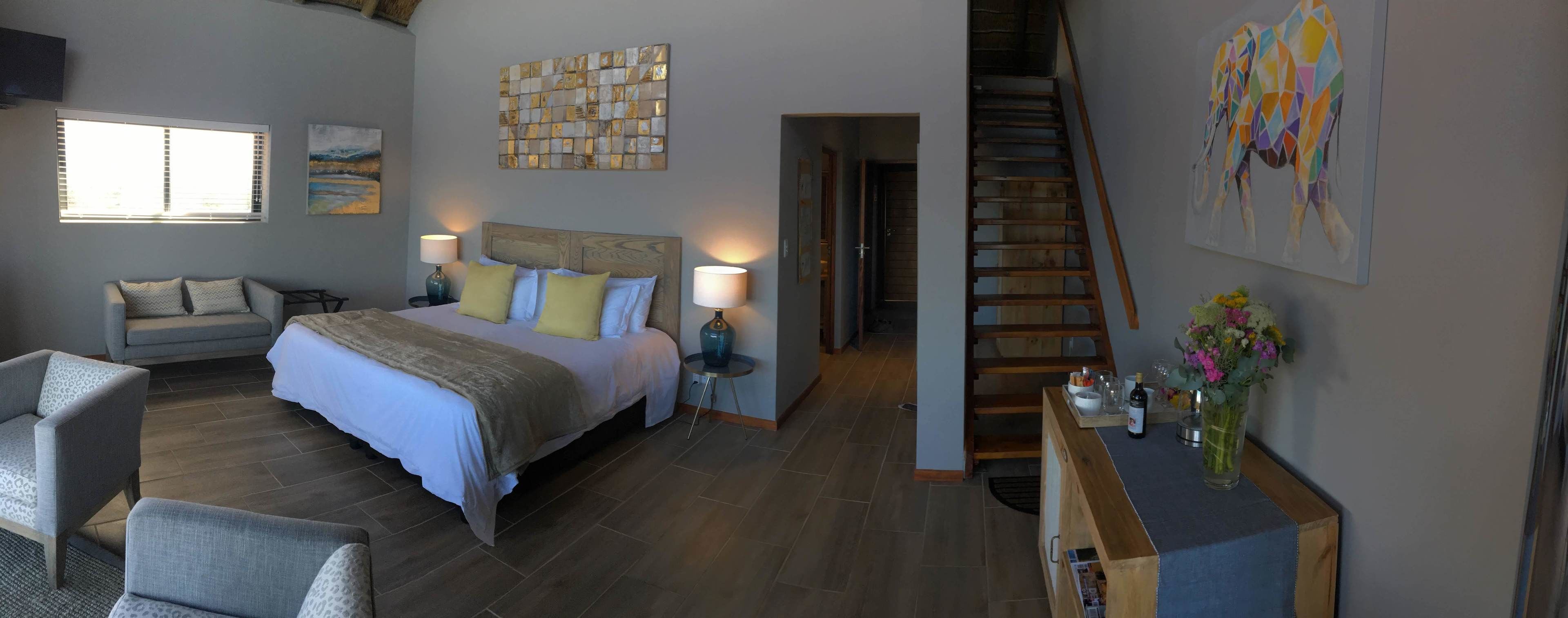 A bedroom with a bed, bedside tables, a chair, a desk, and a staircase.