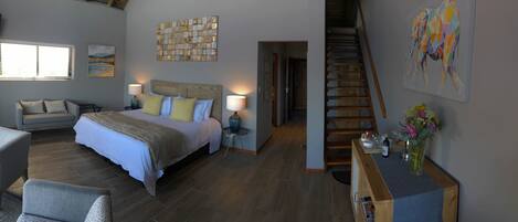 A bedroom with a bed, bedside tables, a chair, a desk, and a staircase.