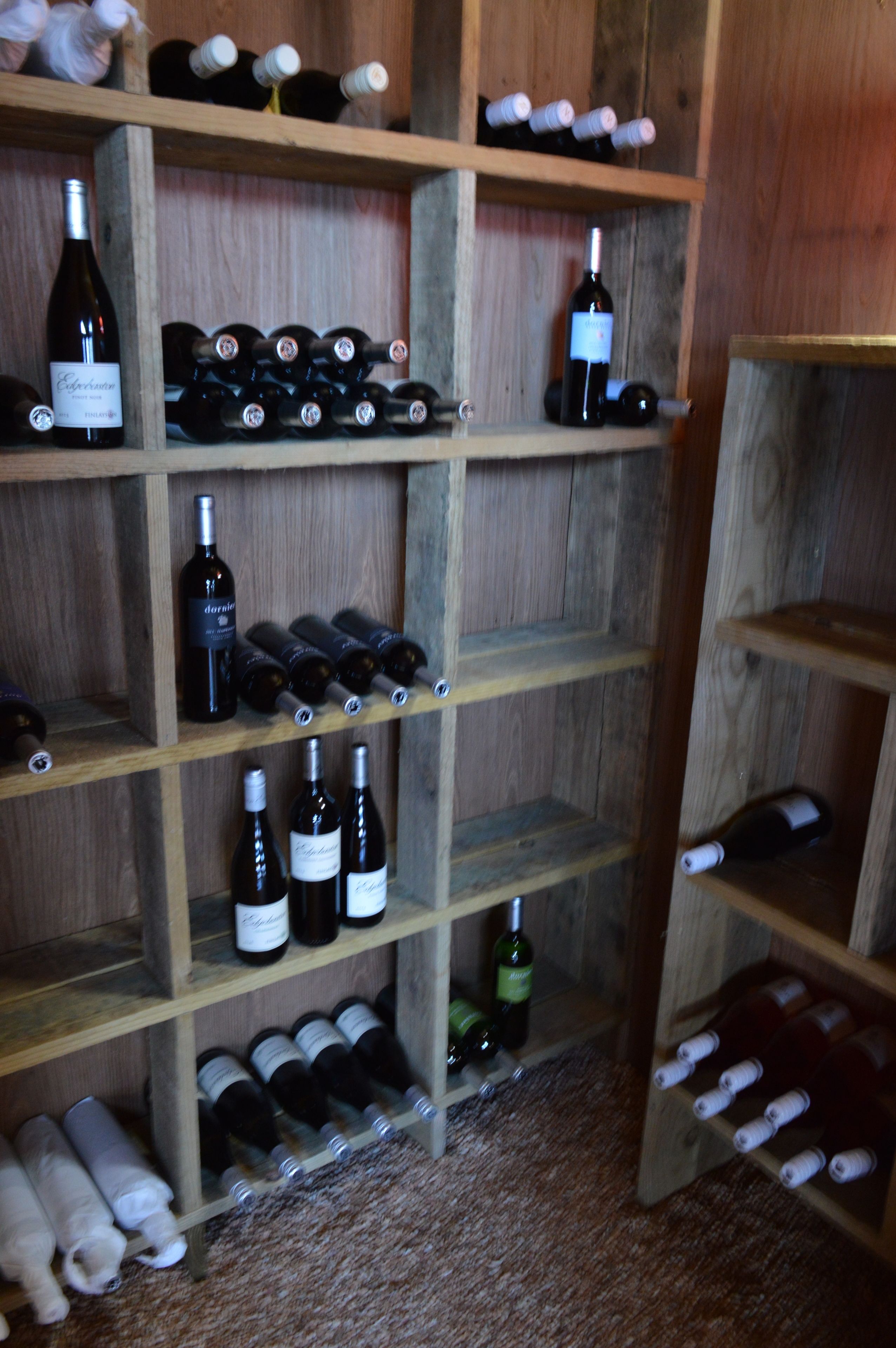 Un porte-bouteilles en bois, doté de plusieurs étagères pour accueillir différentes bouteilles de vin.