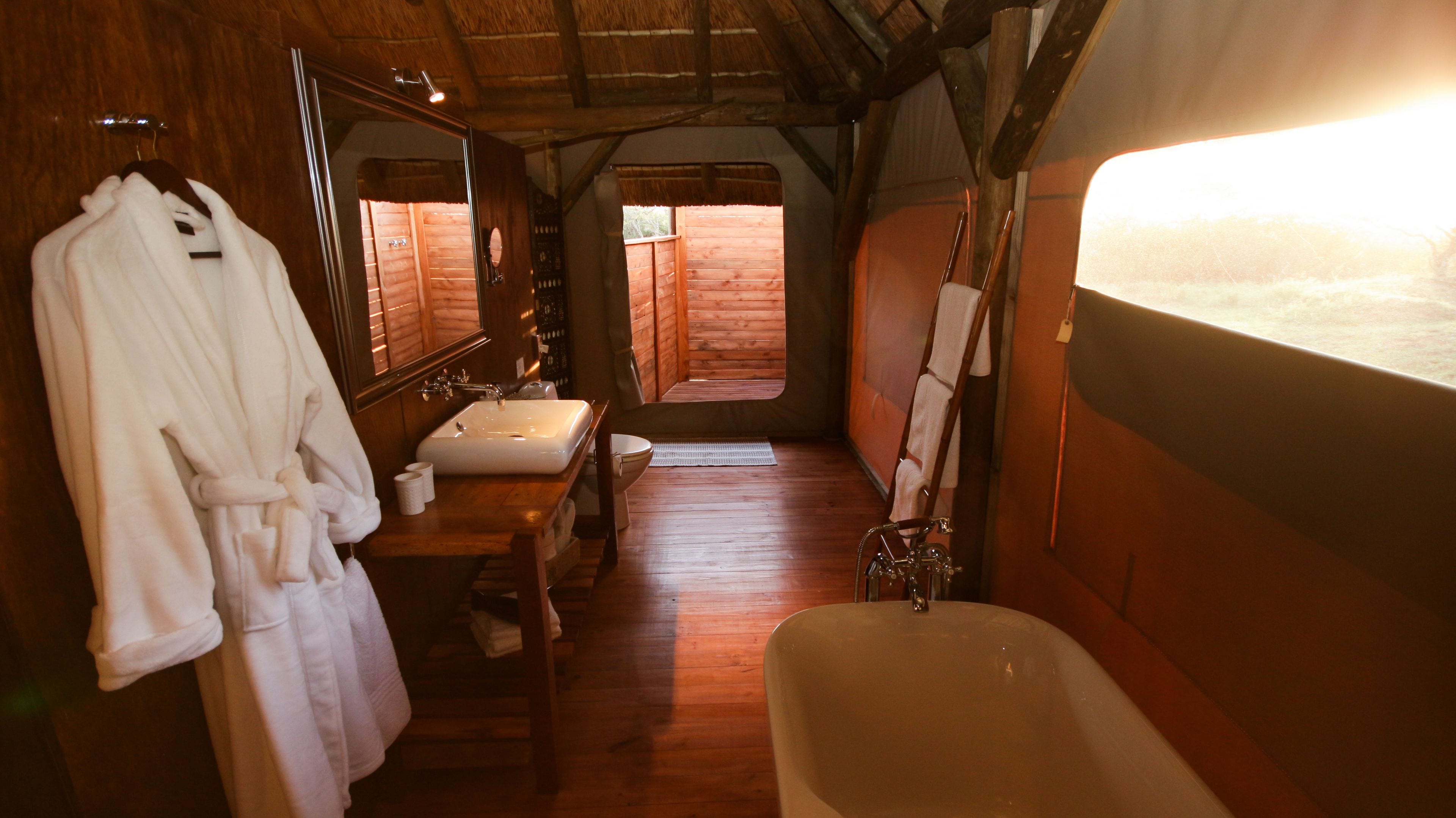 A wooden cabin bathroom with a bathtub, sink, and mirror.