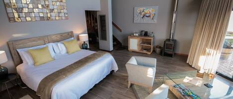 A spacious bedroom with a large bed, a glass coffee table, and a seating area.