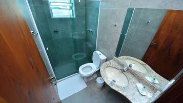 Ein Badezimmer mit einer Duschkabine, einer Toilette und einem Waschbecken mit zwei Becken.