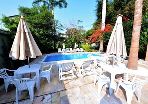 Una piscina al aire libre, sillones reclinables de piscina
