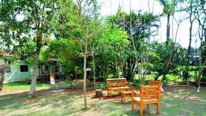 A grassy outdoor area with wooden benches and a small structure. - Hotel Passaledo (Indaiatuba)