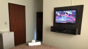 A hotel room with a bed, a television mounted on the wall, and a door. - Hotel Passaledo (Indaiatuba)