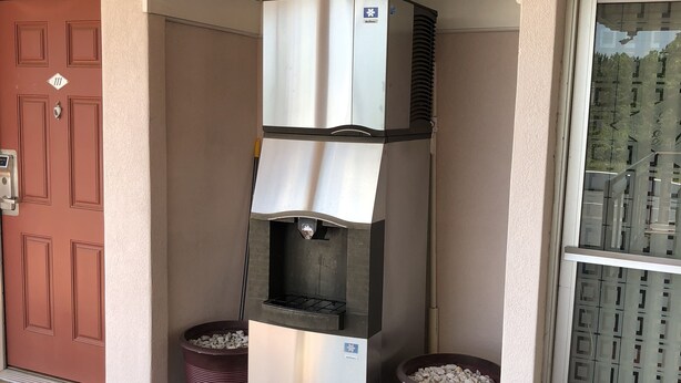 A commercial ice machine with two large pots of ice, a red door, and a glass door with a metal grid. - Budget Inn (Jasper)