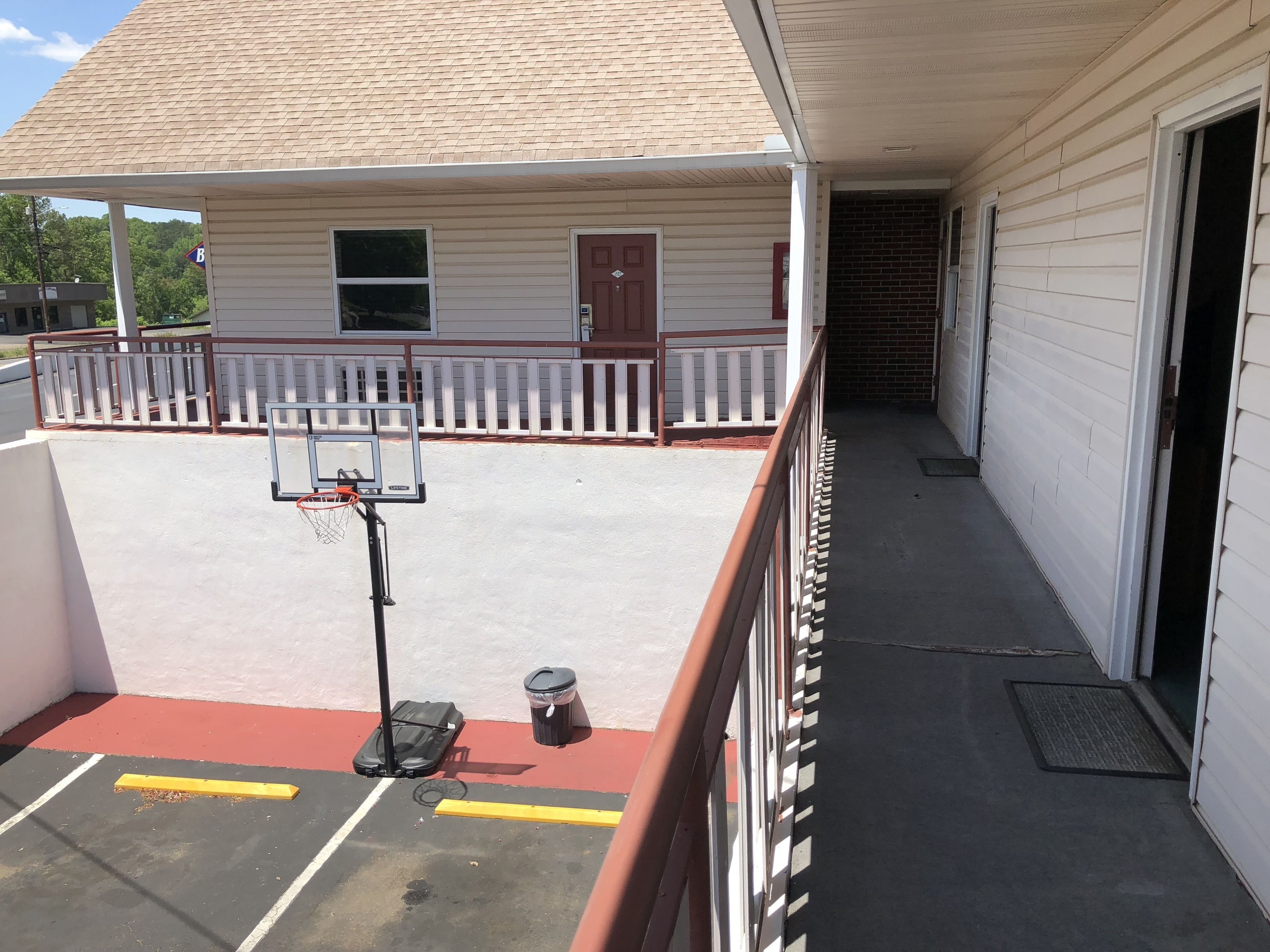 A basketball court with a hoop, a trash can, and a bench.