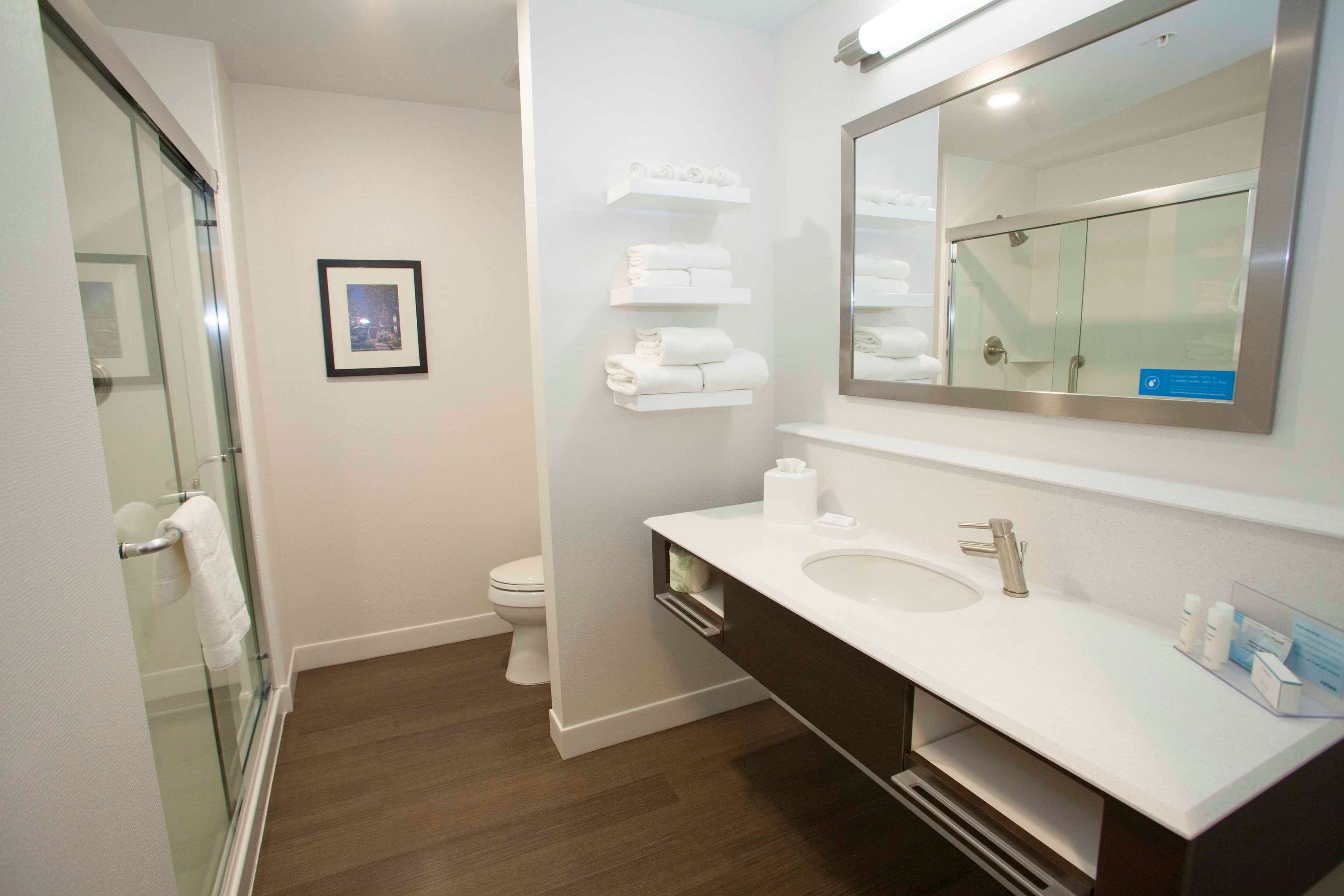 A modern bathroom with a glass shower enclosure, a white sink with a dark vanity, and a large mirror above the sink.