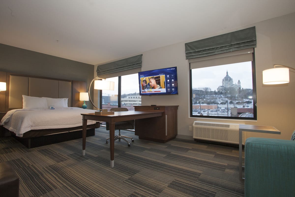 A hotel room with a bed, desk, and TV.
