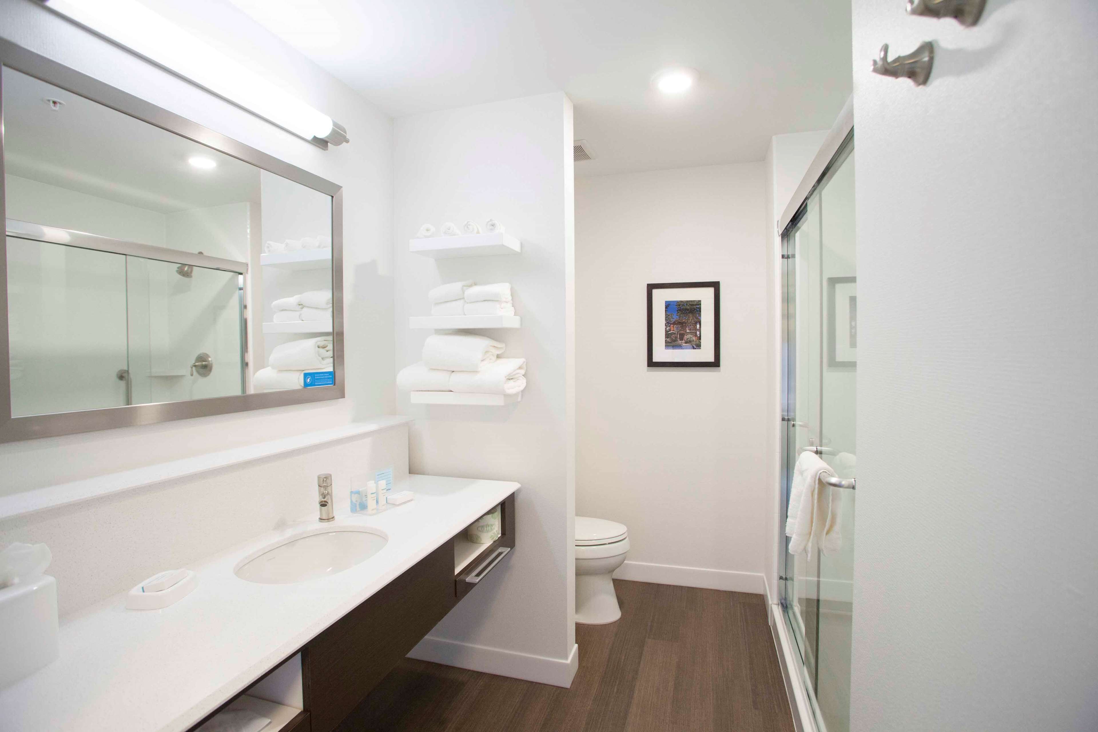 A modern bathroom with a large mirror, a sink, a toilet, and a glass shower enclosure.