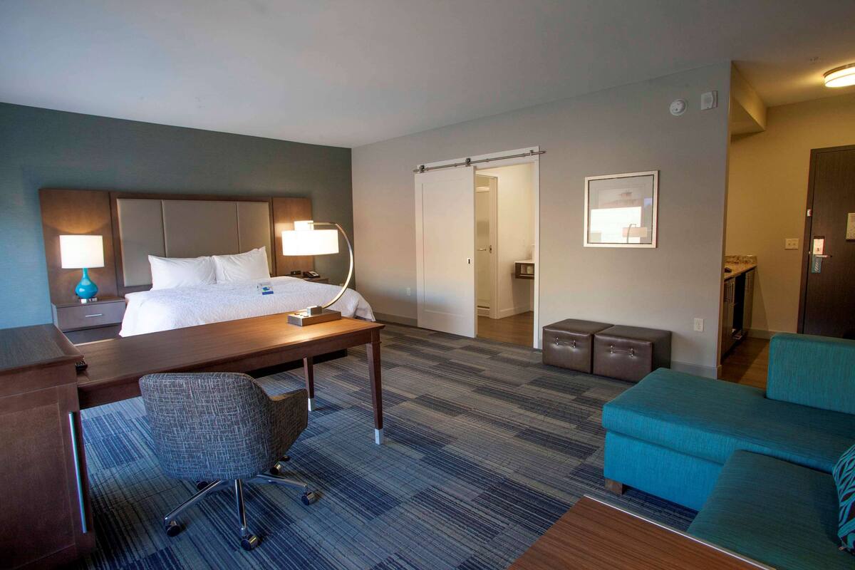 A hotel room with a bed, desk, chair, and a sofa.
