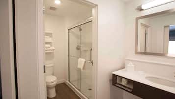 Een badkamer met een douche met glazen wand, een wit toilet en een wastafel met spiegel.