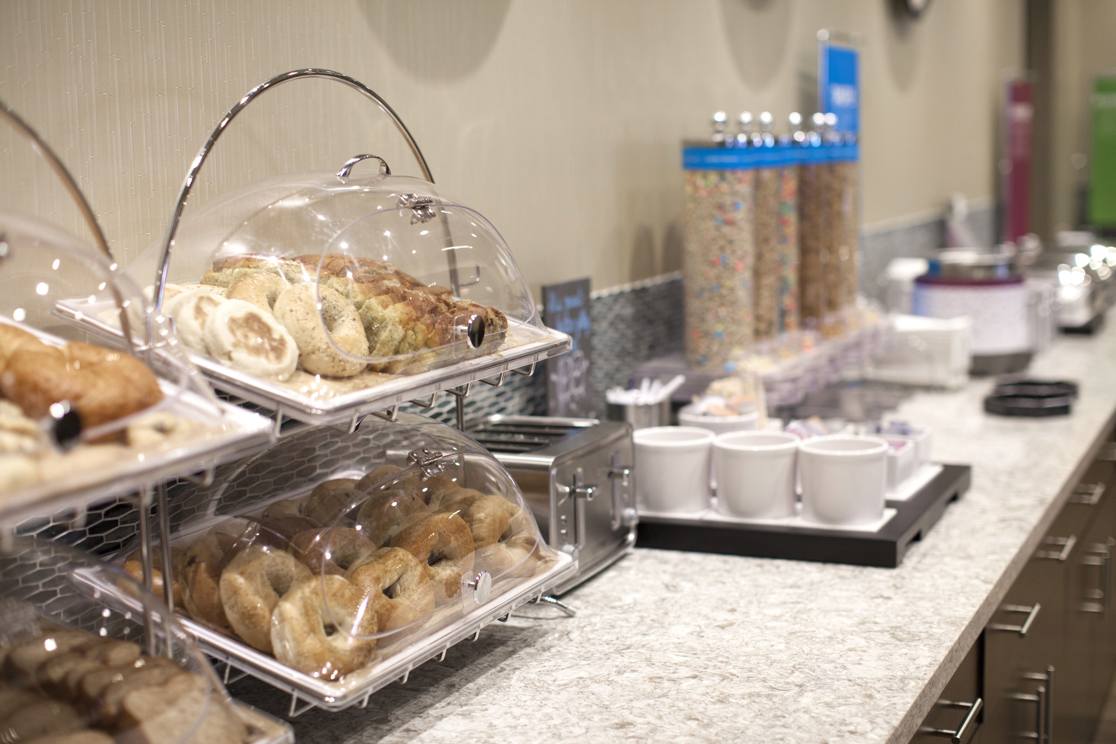 A buffet area with various food items like pastries and donuts displayed in clear containers.