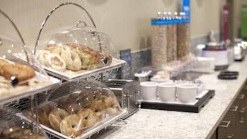 A buffet area with various food items like pastries and donuts displayed in clear containers.