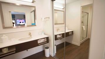 A modern bathroom with a large mirror, two sinks, and a glass shower enclosure.