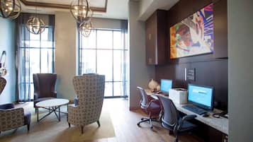 A modern office space with a large window, a desk with a computer, and comfortable seating.