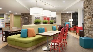 Een modern interieur met een groene bank, rode stoelen, een tafel en hanglampen.