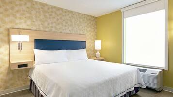 Une chambre d’hôtel avec un grand lit, une table de chevet avec une lampe, un radiateur fixé au mur et une fenêtre donnant sur un beau paysage.