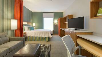 A hotel room with a bed, a desk, a TV, a sofa, and a window.