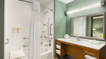 A modern bathroom with a walk-in shower, a bathtub, a vanity with a mirror, and a towel rack.