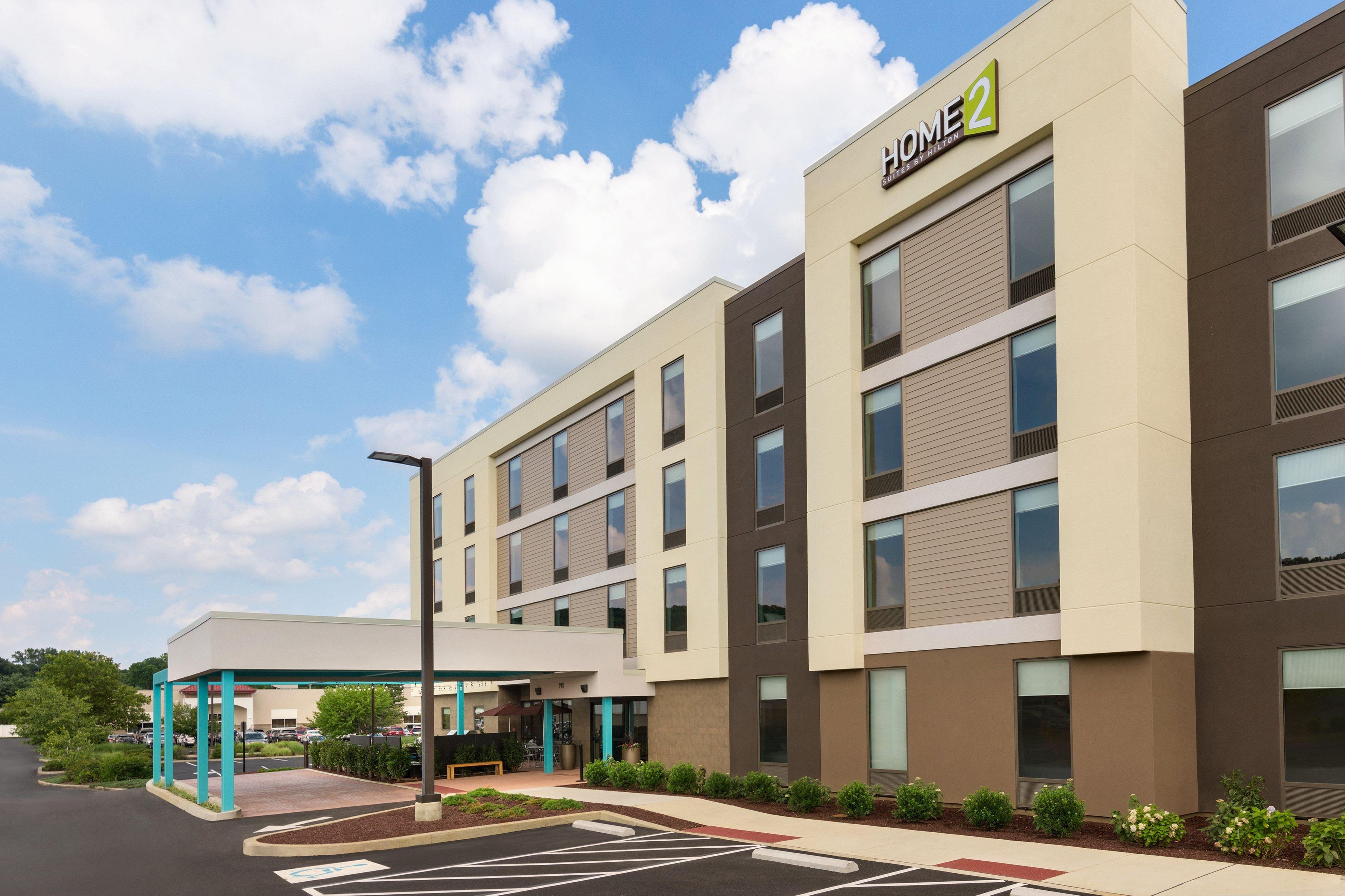 A modern hotel building with a sign reading 'HOME 2' and a covered entrance area.