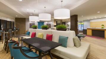 A modern lounge area with a sofa, chairs, a table, and pendant lighting.