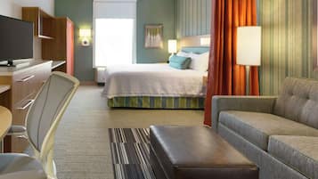 A hotel room with a bed, a sofa, a TV, a desk, and a chair.