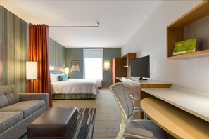 A hotel room with a bed, a sofa, a desk, a TV, and a window.
