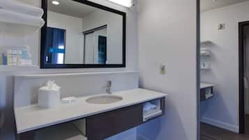 A modern bathroom with a white vanity, a large mirror, and a built-in shelf.