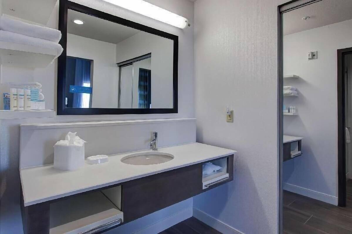 A modern bathroom with a large mirror, a sink, and a towel rack.