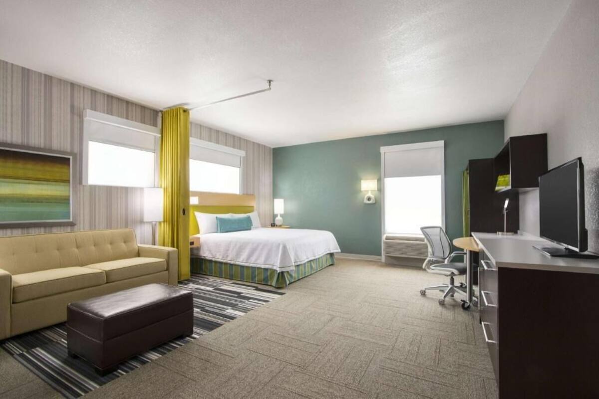 Habitación de hotel con cama, sofá, escritorio y televisor.
