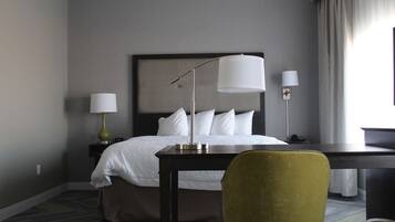 Une chambre d’hôtel comprenant un lit, des tables de chevet, des lampes, un bureau et une chaise.