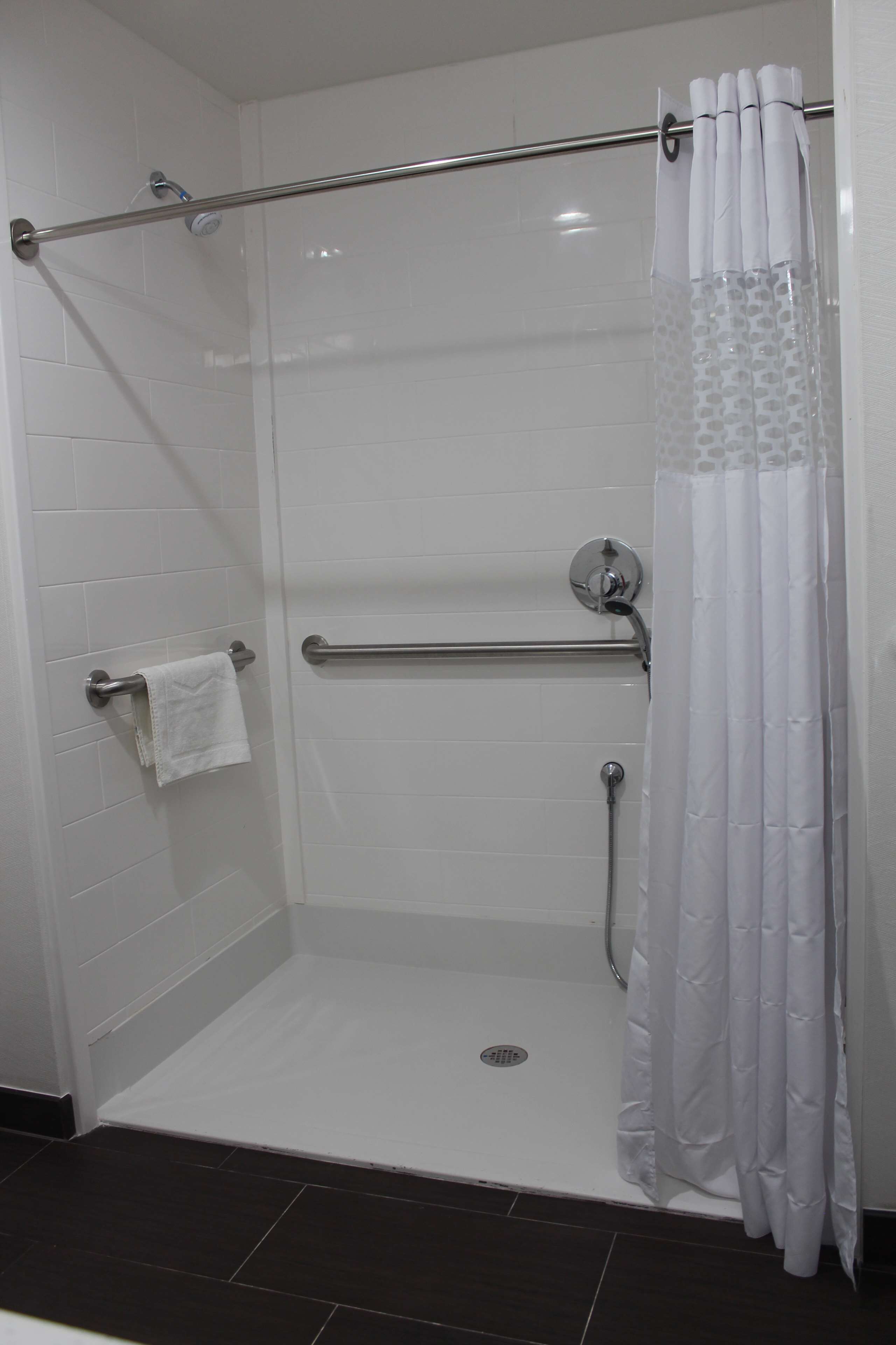 A walk-in shower with a glass door, a towel rack, and a shower curtain.