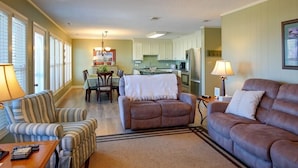 A living room with a sofa, armchair, and a dining area with a table and chairs. - Holden Haven 4 Bedroom Home by RedAwning (Supply)