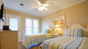 A bedroom with two beds, a ceiling fan, a television, and a wicker chair. - Holden Haven 4 Bedroom Home by RedAwning (Supply)
