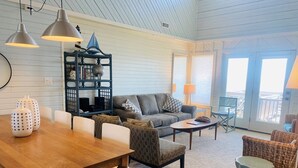 A spacious living area with a wooden dining table, a sofa, a coffee table, and a bookshelf.