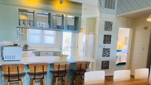 A kitchen with a central island, bar stools, and a dining table.