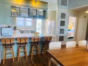 Una cocina con isla central, taburetes de bar y una mesa de comedor.