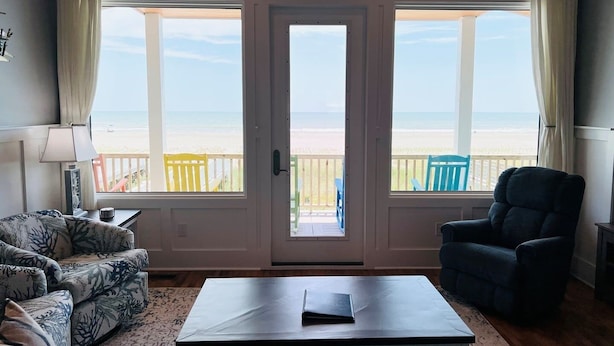 Une pièce avec vue sur la plage, comprenant un canapé, un fauteuil et une table.