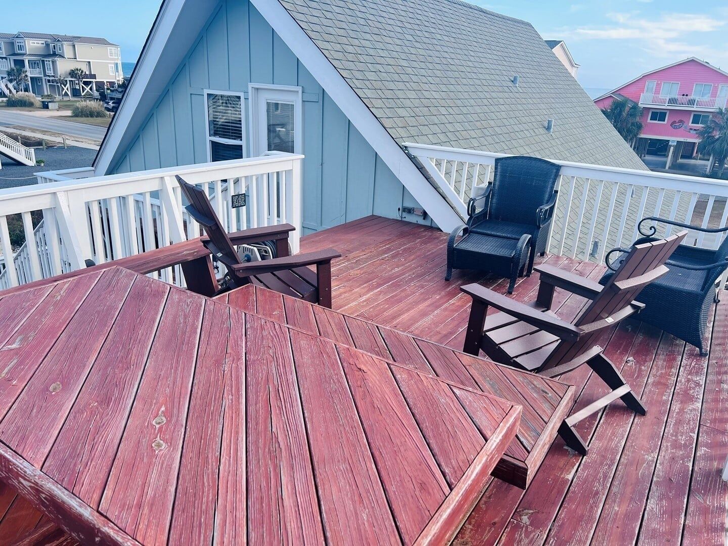 Une terrasse en bois avec deux fauteuils Adirondack et une petite table.