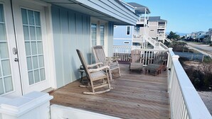 Une terrasse en bois avec des fauteuils à bascule et une balustrade blanche.