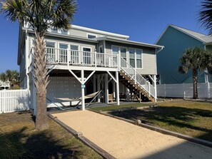 A two-story house with a covered porch, a staircase, and a garage. - How Sweet The Sound 3 Bedroom Home by RedAwning (Supply)