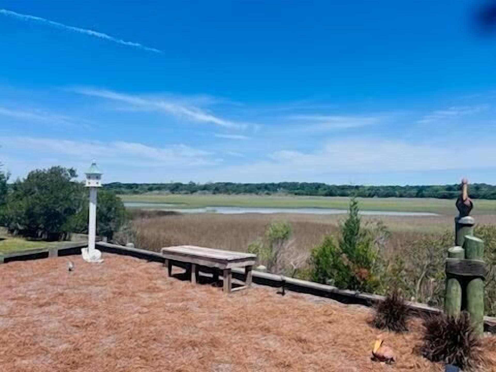 A gazebo with a table and chairs, surrounded by a wooden deck and a view of a distant landscape.