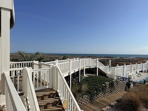 Une terrasse en bois avec des rampes blanches, donnant sur la plage.