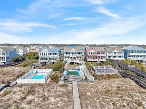 A coastal residential area with multiple two-story houses, a wooden deck, and a swimming pool. - Majak Moments 7 Bedroom Home by RedAwning (Supply)