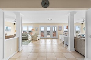 Amplia sala de estar con vistas al exterior, un comedor con mesa blanca y una cocina con muebles blancos.